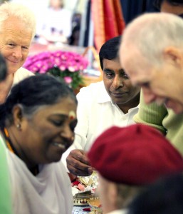 Volunteer Thiru Mahesan (Center) with Amma during a Darshan.