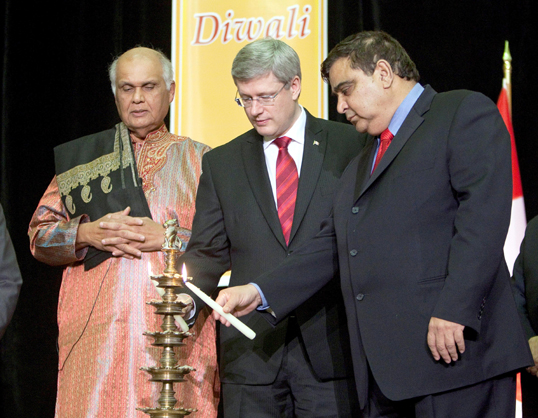 Prime Minister Stephen Harper and Deepak Obrhai, Member of Parliament, light the traditional lamp in celebration of Diwali while Dr. Doobay, Pandit from the Vishnu Mandir, conducts the ceremony in Ottawa. (Pictures by Jason Ransom)