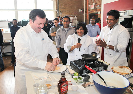 Minister Kenney prepares some hoppers, and decided to add Canadian maple syrup to his recipe, while Chandrika Tilakaratne looks on. 