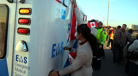 Sitsabaiesan helps to tie Canadian flag on a Toronto ambulance parked on the bridge overlooking Highway 401, referred to as the Highway of Heroes, a route used to repatriate Canadian soldiers killed in the Afghanistan campaign.