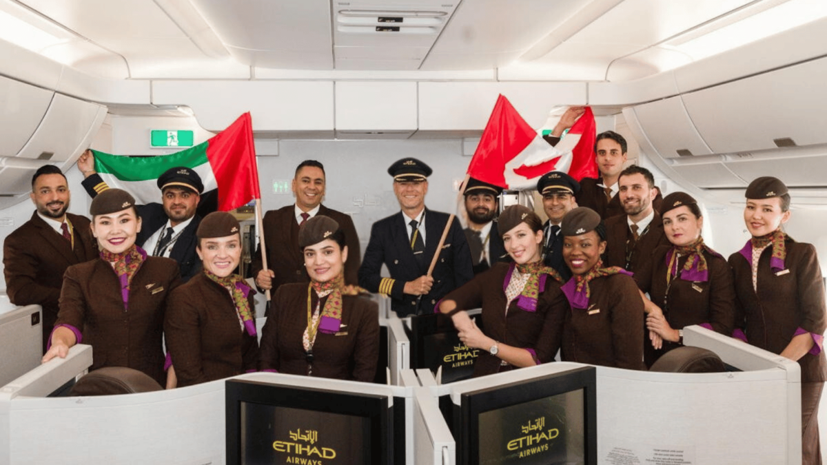 Etihad airways flight and cabin crew inside the aircraft holding Canadian and UAE flags.