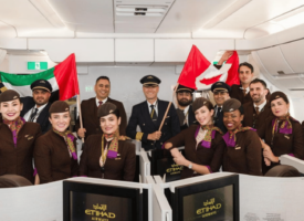 Etihad airways flight and cabin crew inside the aircraft holding Canadian and UAE flags.